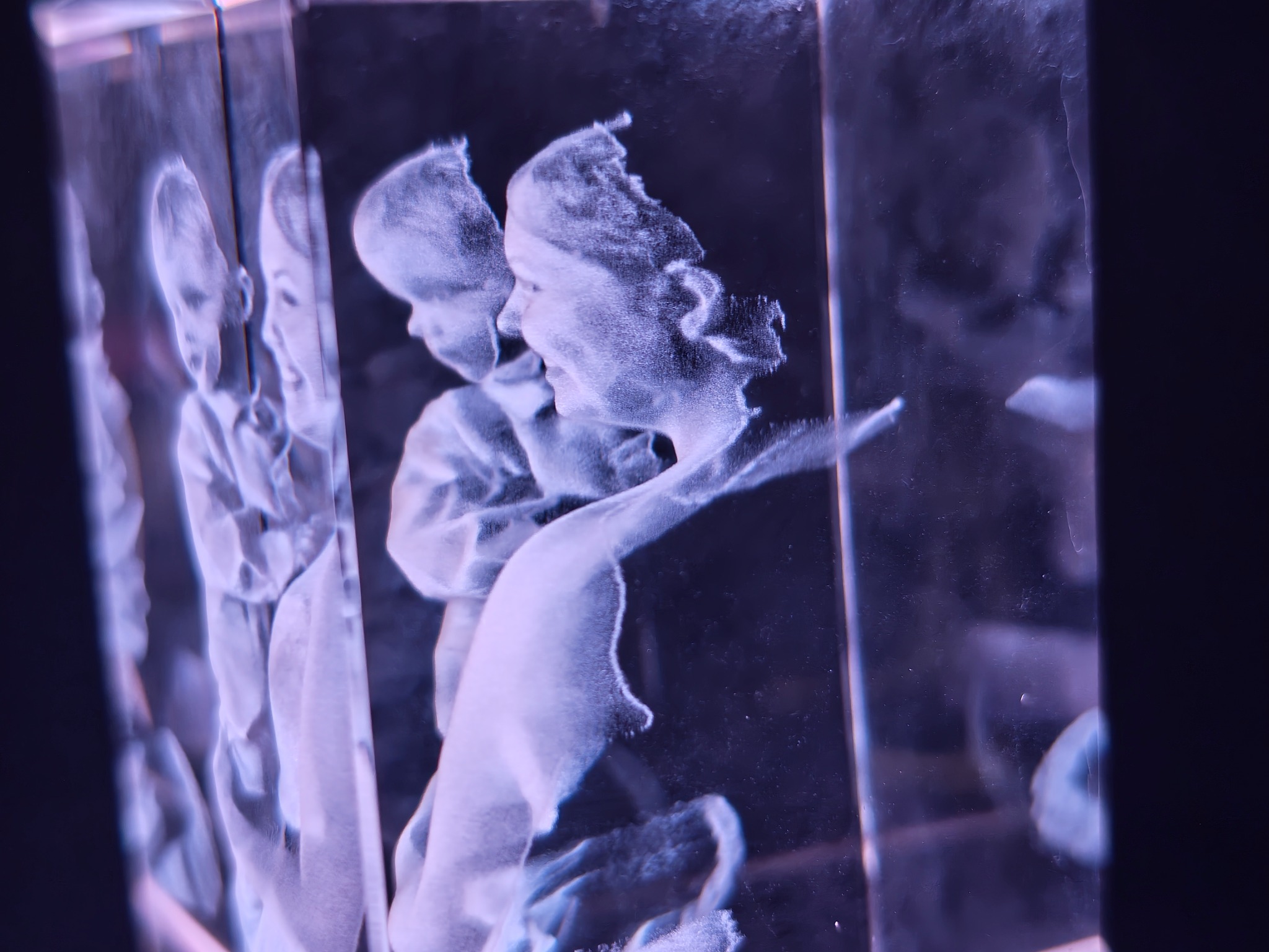 Angled view of a mother and child portrait engraved in a rectangular crystal with purple lighting